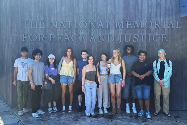 Students beside the national memorial for peace and justice sign